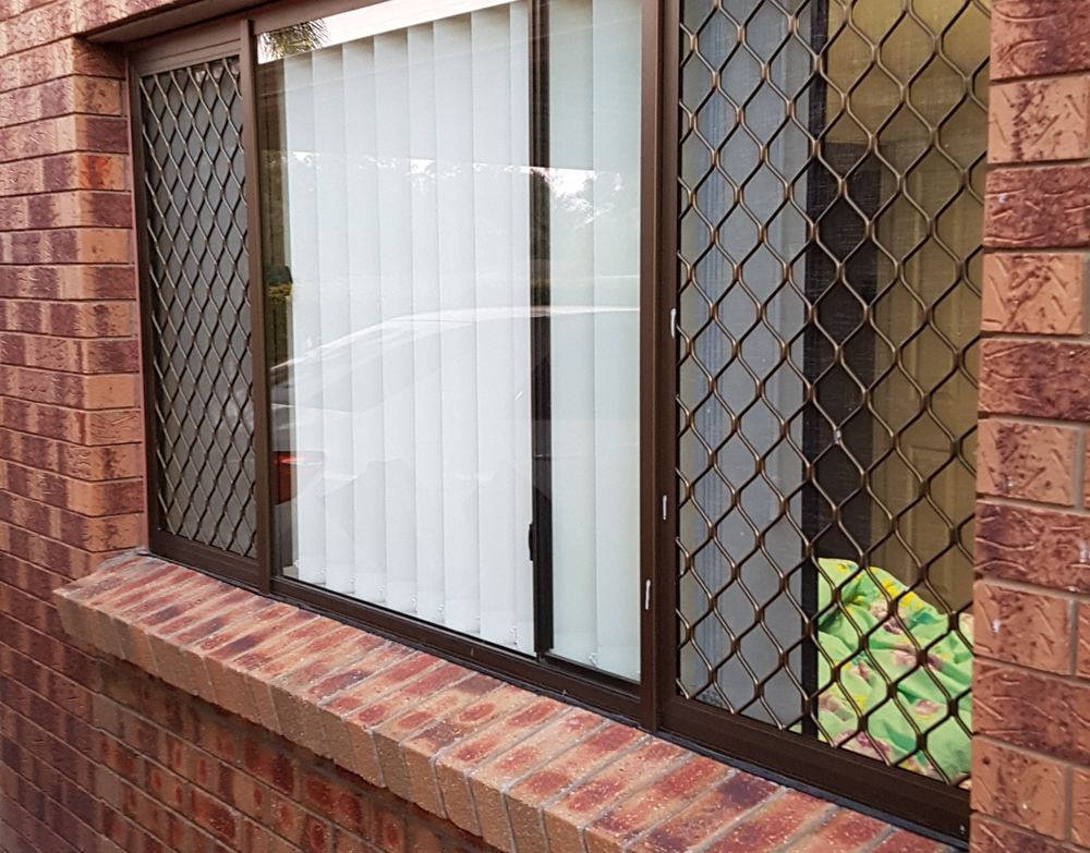 Diamond grille security screens on red brick home windows