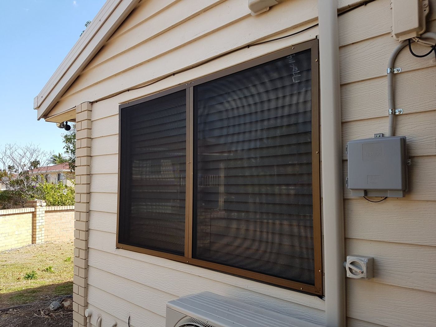 Brown framed security window screens fitted to a weatherboard home